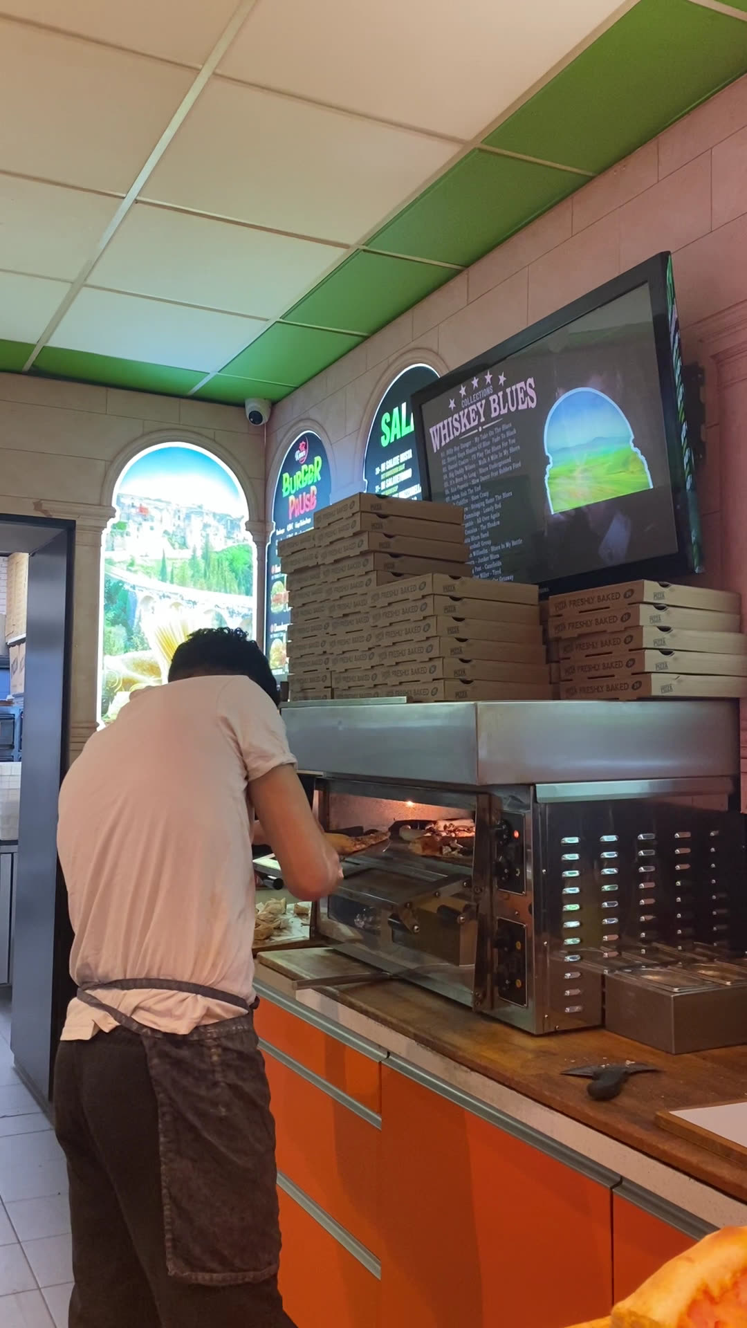 Blick in den Laden: Pizzaofen und gestapelte Pizzakartons
